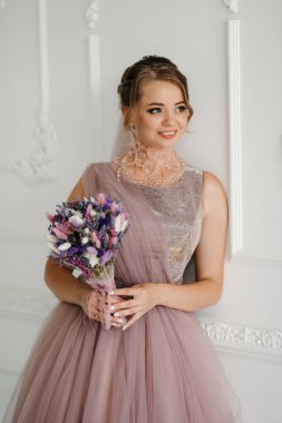 Gelin lavanta renkli pofuduk gelinlik içinde parlak bir stüdyoda buketle