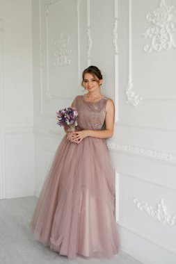 Gelin lavanta renkli pofuduk gelinlik içinde parlak bir stüdyoda buketle