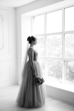 Gelin lavanta renkli pofuduk gelinlik içinde parlak bir stüdyoda buketle