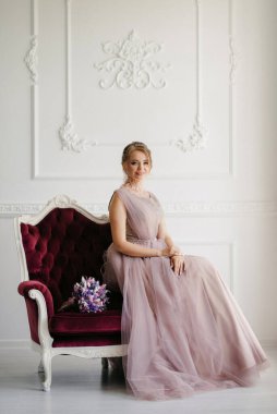 Gelin lavanta renkli pofuduk gelinlik içinde parlak bir stüdyoda buketle