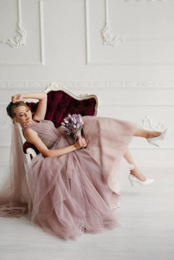 Gelin lavanta renkli pofuduk gelinlik içinde parlak bir stüdyoda buketle