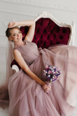 Gelin lavanta renkli pofuduk gelinlik içinde parlak bir stüdyoda buketle