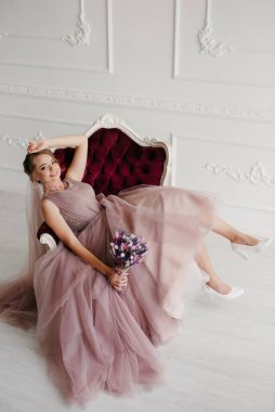 Gelin lavanta renkli pofuduk gelinlik içinde parlak bir stüdyoda buketle