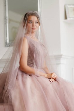 Gelin lavanta renkli pofuduk gelinlik içinde parlak bir stüdyoda buketle