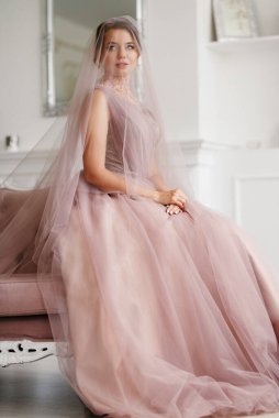 Gelin lavanta renkli pofuduk gelinlik içinde parlak bir stüdyoda buketle