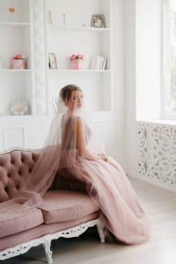 Gelin lavanta renkli pofuduk gelinlik içinde parlak bir stüdyoda buketle