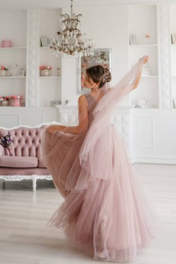 Gelin lavanta renkli pofuduk gelinlik içinde parlak bir stüdyoda buketle