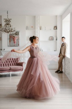 Gelin lavanta renkli pofuduk gelinlik içinde parlak bir stüdyoda buketle