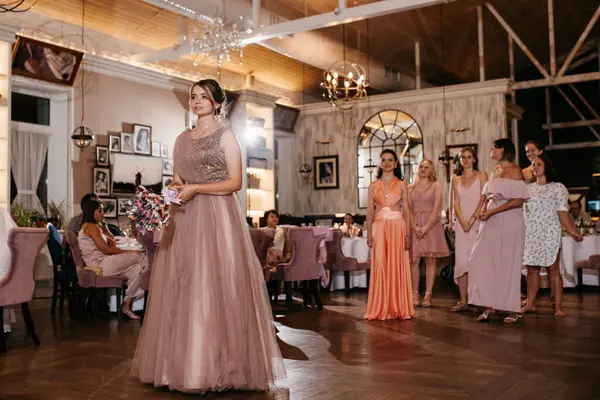bride in a white dress throws a wedding bouquet to her unmarried girlfriends