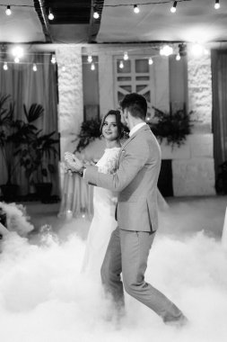 the first dance of the bride and groom inside a restaurant with heavy smoke