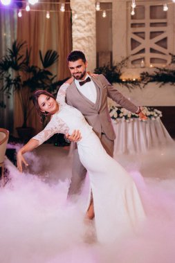 the first dance of the bride and groom inside a restaurant with heavy smoke