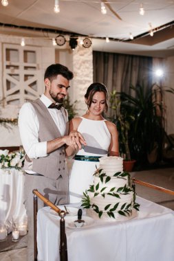 newlyweds happily cut, laugh and taste the wedding cake