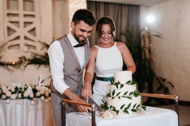 newlyweds happily cut, laugh and taste the wedding cake
