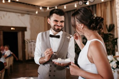 newlyweds happily cut, laugh and taste the wedding cake