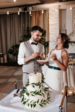 newlyweds happily cut, laugh and taste the wedding cake