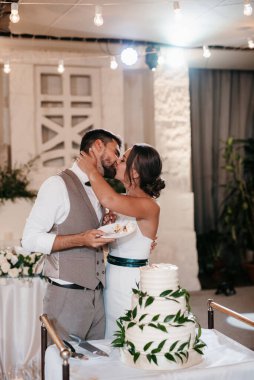 newlyweds happily cut, laugh and taste the wedding cake