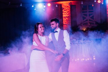 the first dance of the bride and groom inside a restaurant with heavy smoke