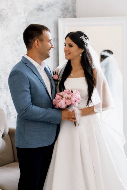 Mavi kravatlı damat ve parlak bir stüdyoda dar beyaz elbiseli gelin.