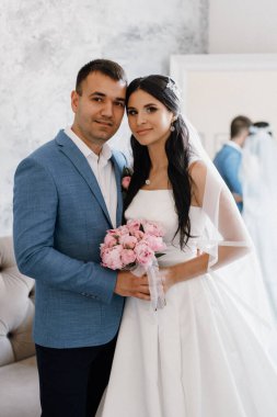 Mavi kravatlı damat ve parlak bir stüdyoda dar beyaz elbiseli gelin.