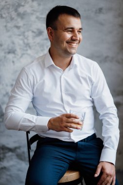 Düğün gününde parlak bir stüdyoda mavi ceketli beyaz gömlekli genç bir damadın portresi.