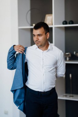 Düğün gününde parlak bir stüdyoda mavi ceketli beyaz gömlekli genç bir damadın portresi.