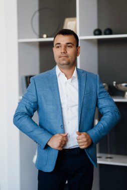 Düğün gününde parlak bir stüdyoda mavi ceketli beyaz gömlekli genç bir damadın portresi.