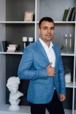 Düğün gününde parlak bir stüdyoda mavi ceketli beyaz gömlekli genç bir damadın portresi.