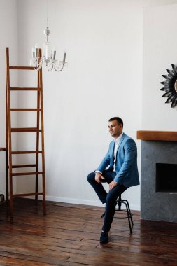 Düğün gününde parlak bir stüdyoda mavi ceketli beyaz gömlekli genç bir damadın portresi.