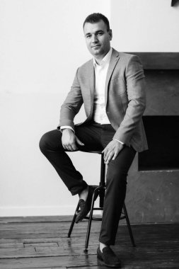 Düğün gününde parlak bir stüdyoda mavi ceketli beyaz gömlekli genç bir damadın portresi.