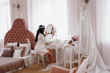 Siyah saçlı gelin kız damadın yatak odasına hazırlanıyor.