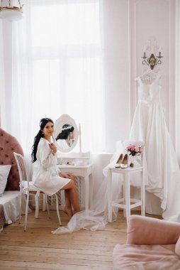Siyah saçlı gelin kız damadın yatak odasına hazırlanıyor.