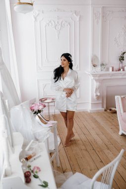 Siyah saçlı gelin kız damadın yatak odasına hazırlanıyor.