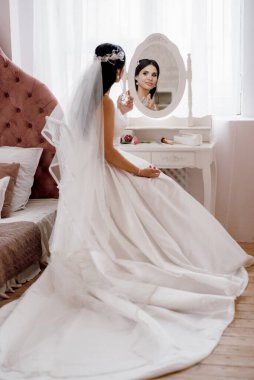 Parlak bir stüdyoda dar bir gelinlik içinde esmer gelin.