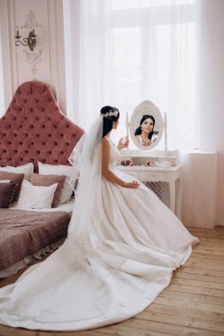 Parlak bir stüdyoda dar bir gelinlik içinde esmer gelin.