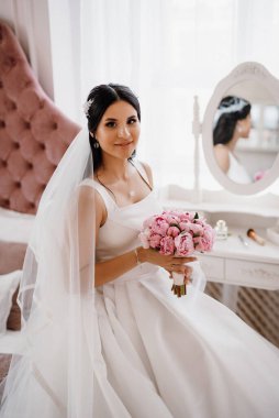 Parlak bir stüdyoda dar bir gelinlik içinde esmer gelin.