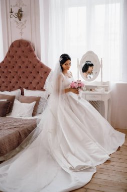 Parlak bir stüdyoda dar bir gelinlik içinde esmer gelin.