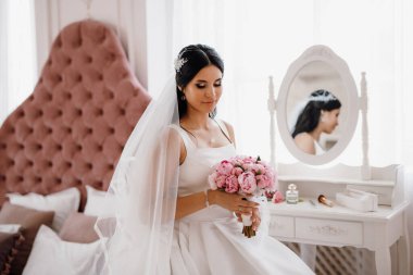 Parlak bir stüdyoda dar bir gelinlik içinde esmer gelin.