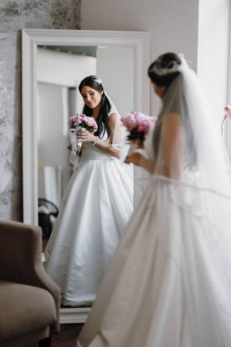 Parlak bir stüdyoda dar bir gelinlik içinde esmer gelin.