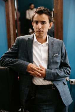 Düğün günü berber dükkanında gri kareli takım elbiseli genç adam.