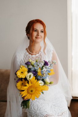 Siyah dantelli gelinlik, sarı buketli otel odasında.