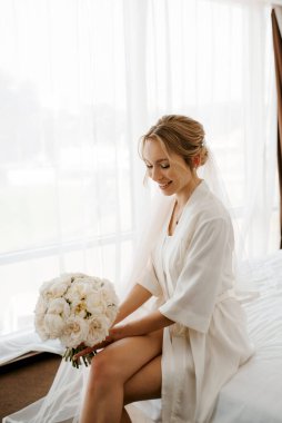 Siyah saçlı gelin kız damadın yatak odasına hazırlanıyor.