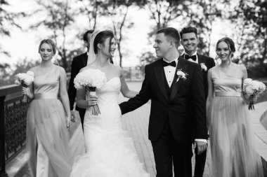 Gelin ve damat düğün günlerinde arkadaşları ve kız arkadaşlarıyla parkta yürüyorlar.