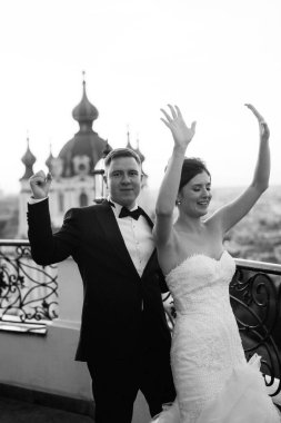 Şehrin ve nehrin zeminine karşı yüksek bir binanın çatısında genç bir çift gelin ve damat