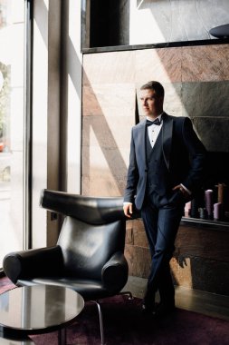 Otel içinde mavi smokinli damadın portresi.