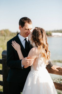 Gelin ve damat gün batımında parkta yürüyor.