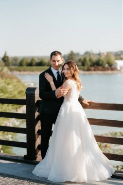 Gelin ve damat gün batımında parkta yürüyor.