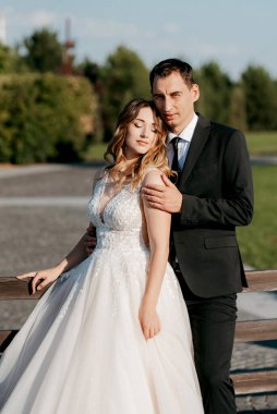 Gelin ve damat gün batımında parkta yürüyor.