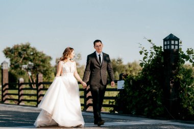 Gelin ve damat gün batımında parkta yürüyor.