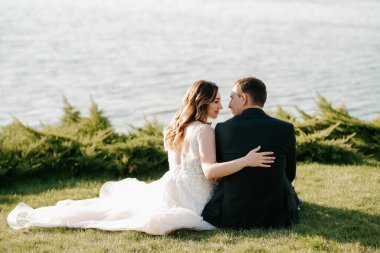 Gelin ve damat gün batımında parkta yürüyor.