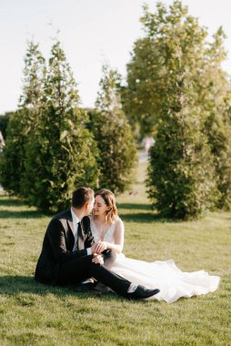 Gelin ve damat gün batımında parkta yürüyor.